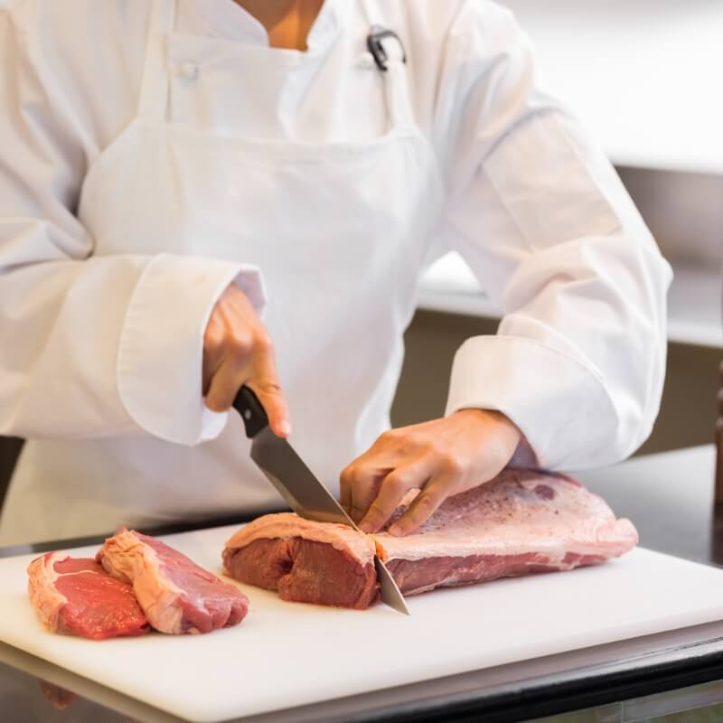 A butcher carefully cutting some meat